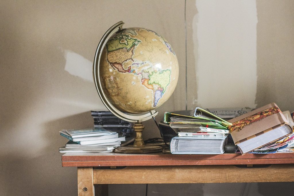 Photo d'une mappemonde posé sur une table en bois avec des albums photos et des CD pour mon article éviter l’accumulation d’objets au fil du temps.